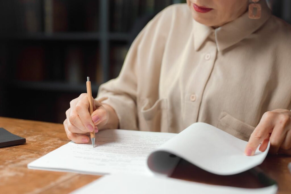 A woman editing a physical manuscript with a pen.
